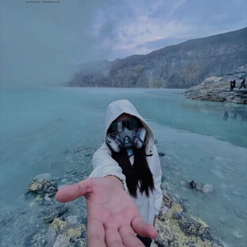 Traveler wearing a gas mask and protective clothing at Kawah Ijen Crater Lake, Banyuwangi, East Java, Indonesia. The turquoise volcanic lake, sulfur mist, and dramatic crater landscape create a unique adventure experience at Mount Ijen.
