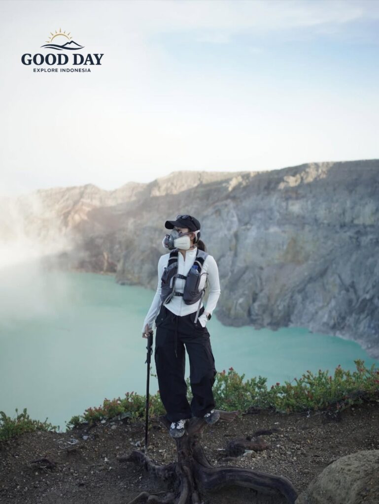 Traveler wearing a safety mask standing beside the turquoise crater lake of Kawah Ijen, Banyuwangi, East Java, Indonesia. The volcanic landscape, sulfur fumes, and dramatic crater walls create one of Indonesia’s most iconic natural attractions.