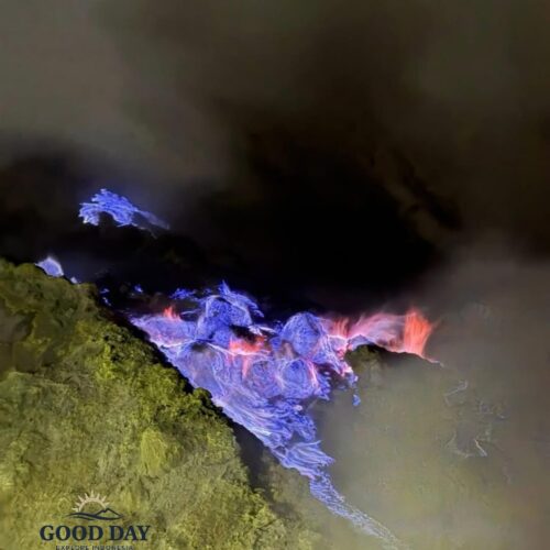Blue fire phenomenon at Kawah Ijen, Banyuwangi, East Java, Indonesia. Electric-blue flames emerge from sulfur deposits in the volcanic crater at night, surrounded by thick smoke and rugged volcanic rocks.