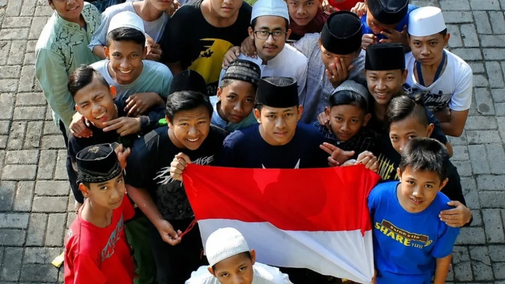 Smiling Indonesian Muslim children proudly holding the Indonesian flag while celebrating their national identity and unity in Indonesia.