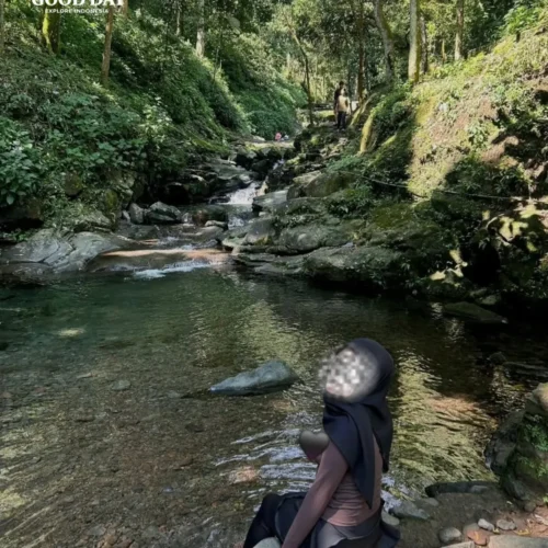 A canyoning participant rappelling down Curug Nangka Waterfall in Bogor, Indonesia, surrounded by lush rainforest during a guided adventure by Good Day.